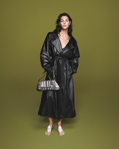 model wearing a black trench coat with a silver Gucci horsebit chain bag