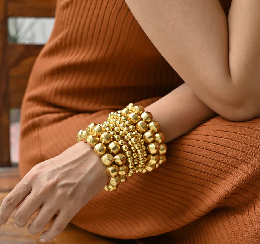 stack of gold bracelets on a models hand 