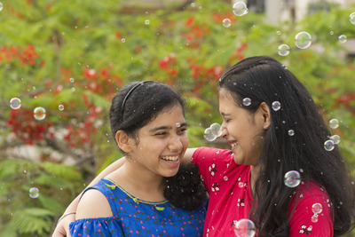 two girl friends laughing with bubbles all around 